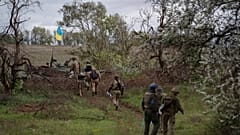 Ukrainian national guard servicemen walk next to a damaged Russian tank