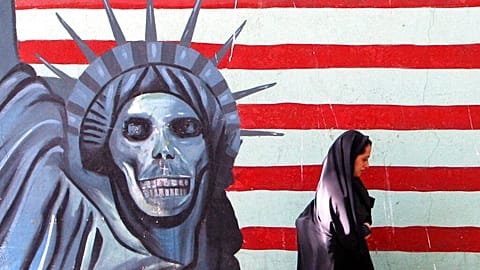 A veiled Iranian woman walks past an anti U.S painting on the wall of the former U.S Embassy in Tehran, Saturday, July 2, 2005. 