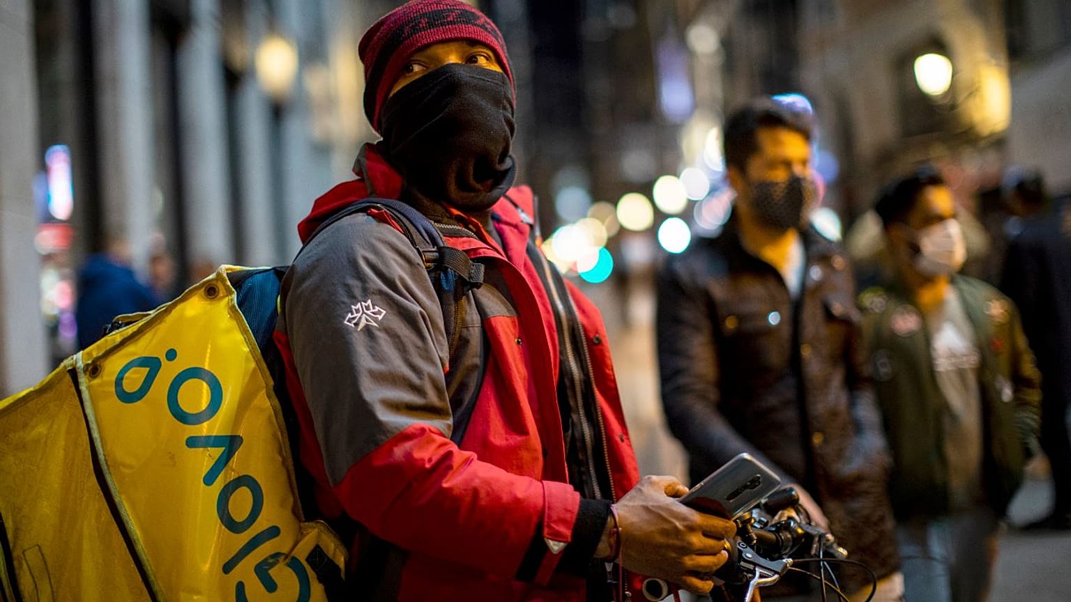 A Glovo food delivery courier stands next to Sol square in Madrid.