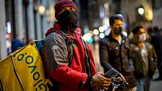 A Glovo food delivery courier stands next to Sol square in Madrid.