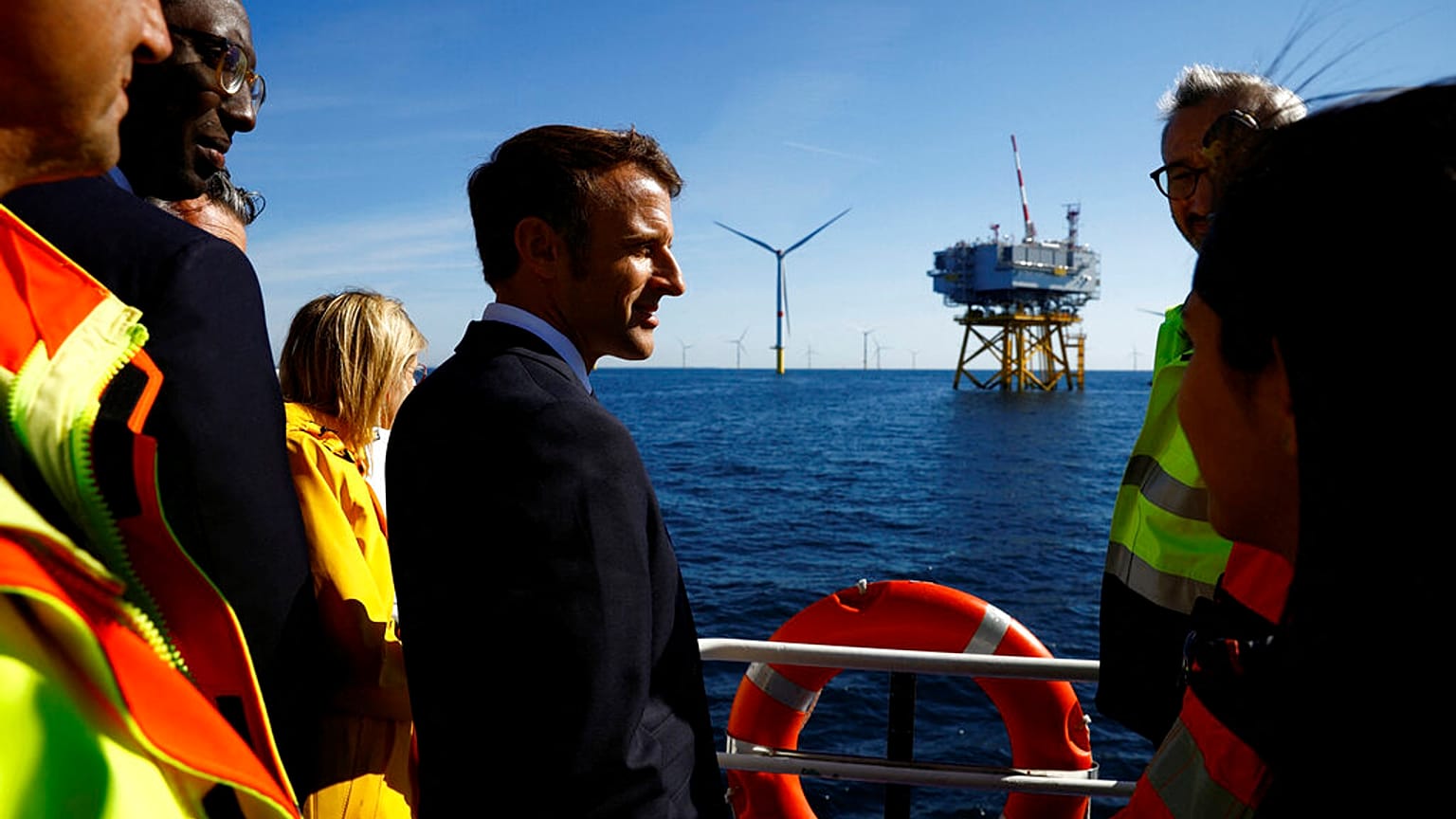 Le président français Emmanuel Macron discute avec des travailleurs à bord d'un bateau lors d'une visite au parc éolien offshore de Saint-Nazaire, 22/09/22