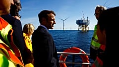 Le président français Emmanuel Macron discute avec des travailleurs à bord d'un bateau lors d'une visite au parc éolien offshore de Saint-Nazaire, 22/09/22