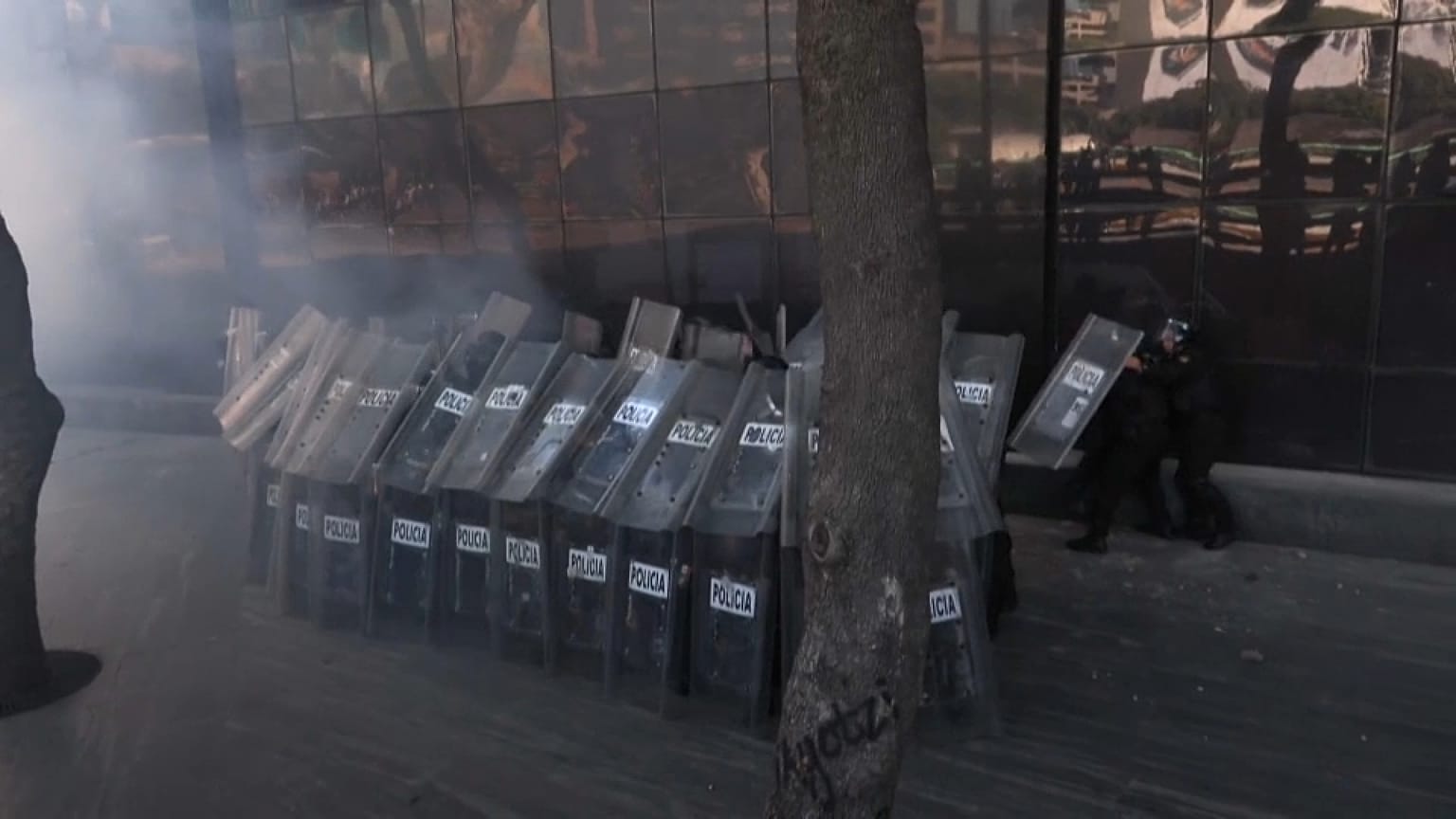 Policías parapetados mientras les lanzan proyectiles ante la Fiscalía General de la República en Ciudad de México