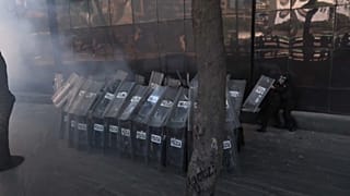 Policías parapetados mientras les lanzan proyectiles ante la Fiscalía General de la República en Ciudad de México