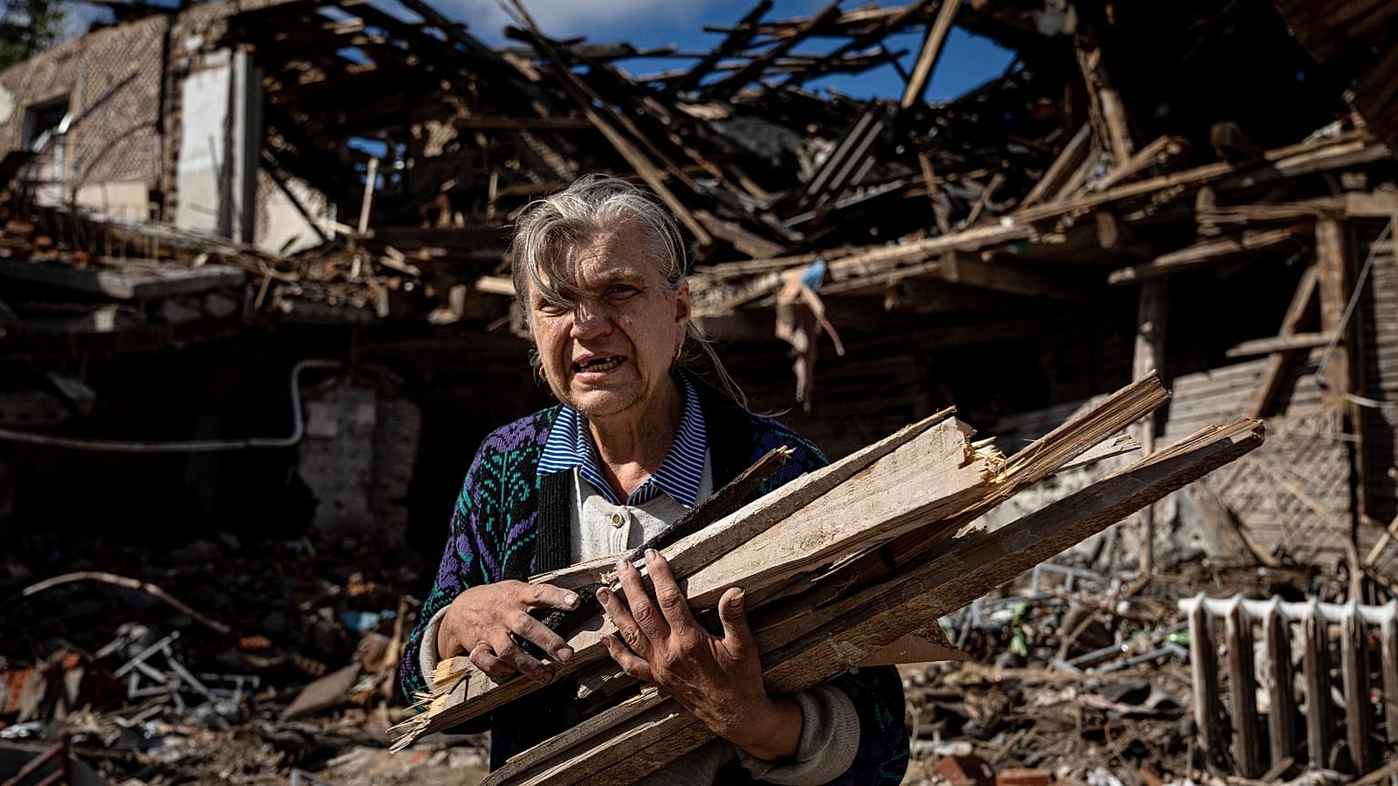 A woman collects wood for heating from a destroyed school where Russian forces were based in the recently retaken area of Izium, Ukraine, Monday, Sept. 19, 2022. 