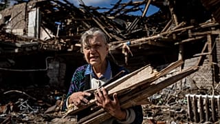 A woman collects wood for heating from a destroyed school where Russian forces were based in the recently retaken area of Izium, Ukraine, Monday, Sept. 19, 2022. 