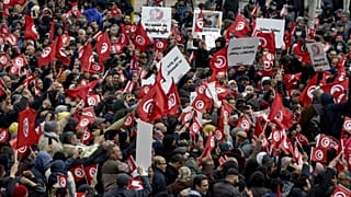 متظاهرون تونسيون يرفعون لافتات وأعلام وطنية، في العاصمة تونس، 20 مارس 2022.