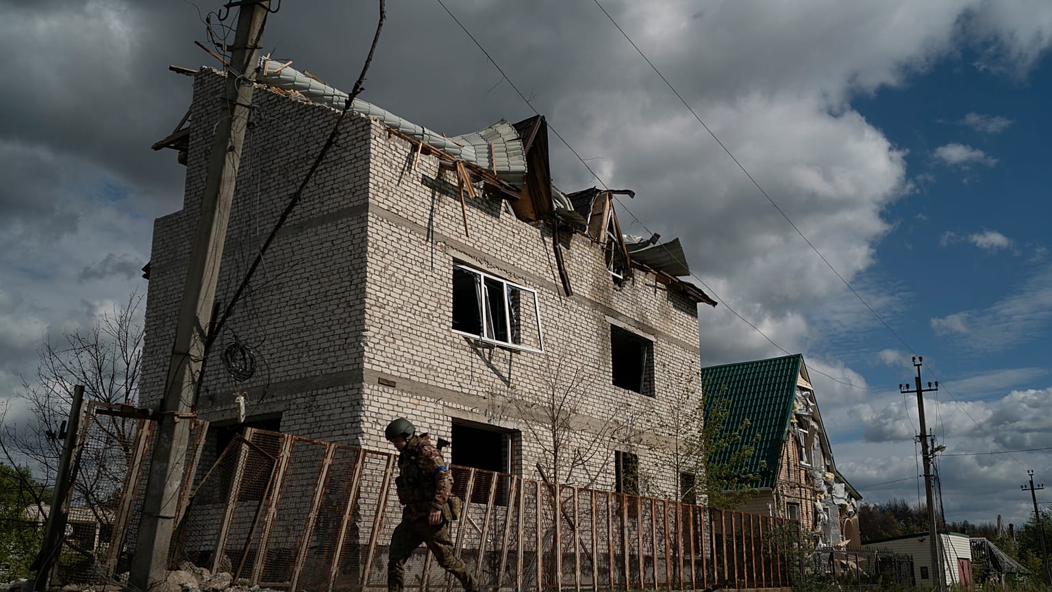 A Ukrainian serviceman from Dnipro-1 regiment walks past a damaged building in the retaken village of Shchurove.