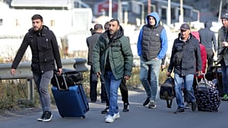 A group of Russians walk after crossing the border at Verkhny Lars between Georgia and Russia in Georgia, Tuesday, Sept. 27, 2022.