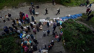 Люди ждут получени�� гуманитарной помощи на пункте раздачи в недавно взятом городе Изюм, Украина, воскресенье, 25 сентября 2022 года