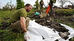 Un soldat ukrainien examine les restes d'un camarade tué lors d'une bataille contre les troupes russes dans la région de Kharkiv, en Ukraine, lundi 26 septembre 2022. 