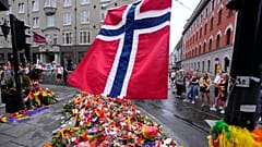 A Norwegian national flag flutters over flowers and rainbow flags near the London Pub in Oslo.
