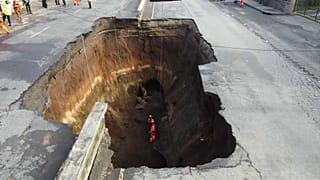 Equipos de rescate dentro del gigantesco socavón abierto en una calle de Villa Nueva, Guatemala