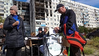 People vote at a mobile polling station in front of a damaged building in Mariupol in eastern Ukraine, Sept 24, 2022