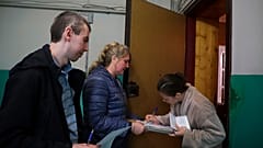Nő szavaz a donyecki "népszavazáson" a választási biztosok viszla tekintete előtt