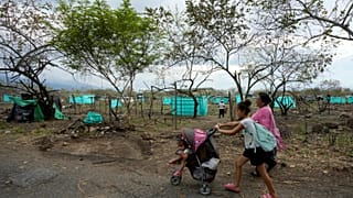 Una familia de ocupantes informales camina frente a unas tiendas de campaña improvisadas después de que la policía los desalojara de un terreno en Neiva, el 28 de septiembre.