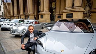Le PDG du constructeur automobile Porsche, Oliver Blume, s'agenouille à côté de voitures Porsche au début de la cotation de Porsche à la bourse de Francfort