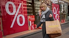 A woman walks with purchases past a store in Berlin, April 1, 2022. 