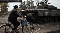 A local resident rides past an abandoned Russian tank marked Z in Kyrylivka, in the recently retaken area near Kharkiv, on September 30, 2022.
