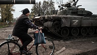 A local resident rides past an abandoned Russian tank marked Z in Kyrylivka, in the recently retaken area near Kharkiv, on September 30, 2022.