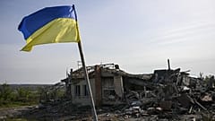 Eine ukrainische Fahne weht vor einem zerstörten Gebäude