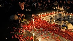 Люди приносят цветы и свечи к мемориалу в память о погибших в давке на стадионе в Маланге.