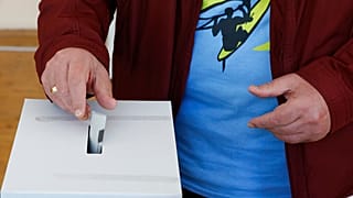 Un homme glissant son bulletin dans l'urne d'un bureau de vote à Sofia, dimanche 2 octobre 2022.