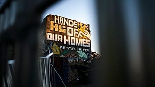 Ein Graffiti mit dem Slogan "Hände weg von unseren Häusern" an der Hauswand eines alternativen Wohnprojekts in Berlin
