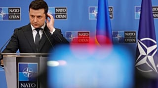 Volodymyr Zelenskyy adjusts his headphone as he participates in a media conference with NATO Secretary General Jens Stoltenberg at NATO headquarters in Brussels