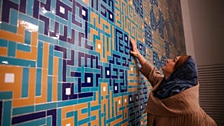  كاترين سبيريدونوف، مهندسة معمارية مشتركة لمسجد ولي العصر تلامس البلاط الملون الذي يزين محراب المسجد، في طهران، إيران، في 7 فبراير 2018 