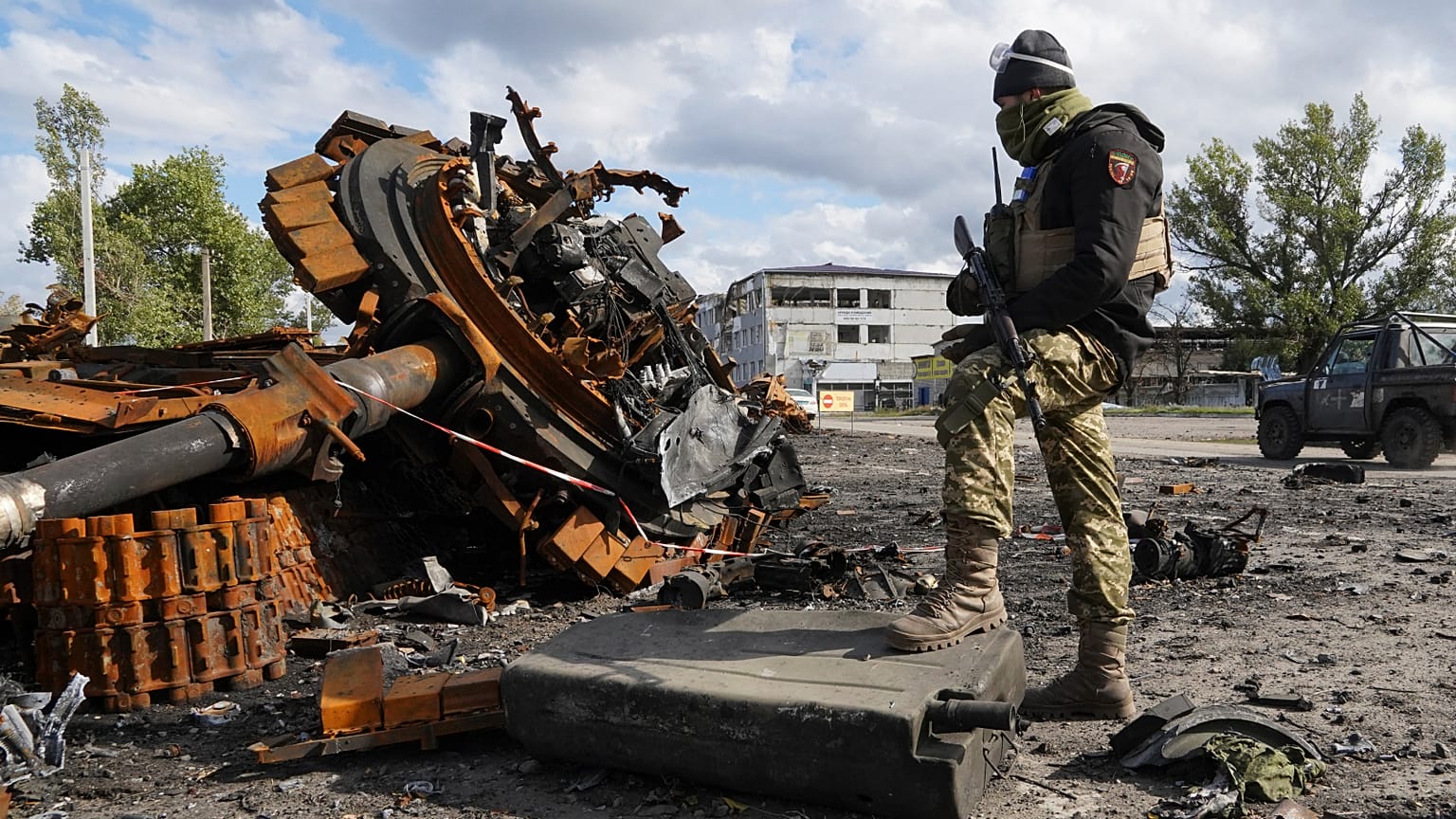 A Ukrainian soldier stands near a damaged Russian tank in Kupyansk in the Kharkiv region, which has sustained Russian shelling - pictured Oct. 4, 2022. 