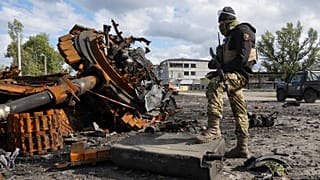 A Ukrainian soldier stands near a damaged Russian tank in Kupyansk in the Kharkiv region, which has sustained Russian shelling - pictured Oct. 4, 2022. 