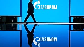Мужчина идет по выставке на Петербургском международном газовом форуме в Санкт-Петербурге, Россия, в среду, 14 сентября 2022 года, с логотипом российской газовой монополии "Газпром" в