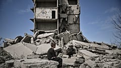Un jeune garçon est assis devant un bâtiment détruit après un bombardement à Kramatorsk dans le Donbass