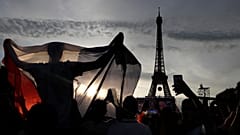 A supporter displays a French flag in the Paris fan zone in front of the Eiffel Tower during the Euro 2016 final soccer match between Portugal and France.