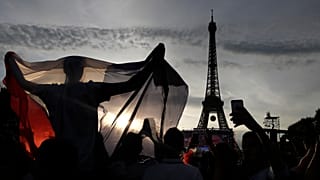 A supporter displays a French flag in the Paris fan zone in front of the Eiffel Tower during the Euro 2016 final soccer match between Portugal and France.