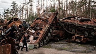Policier ukrainien devant des carcasses de chars russes à Lyman, le 5 octobre 2022