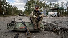 A Ukrainian serviceman smokes a cigarette after he finds and identifies a dead body of a comrade in recently recaptured town of Lyman, Ukraine, Monday, Oct. 3, 2022