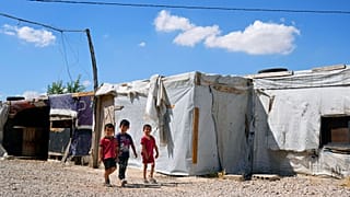 Syrian children walk past their family tents at a refugee camp in the town of Bar Elias, in Lebanon's Bekaa Valley, Tuesday, June 13, 2023. 