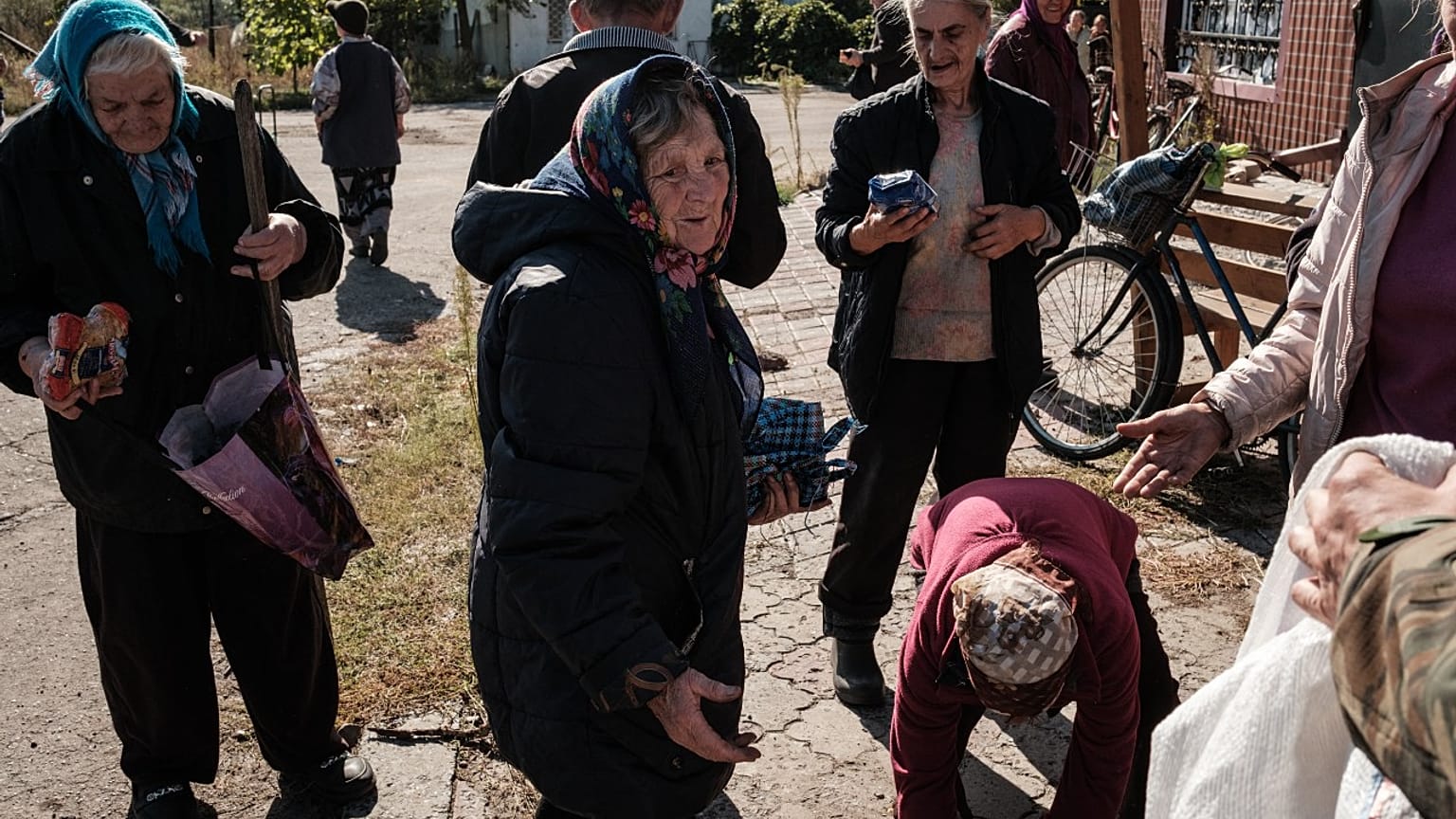 Local residents take some food distributed by a Ukrainian soldier in Yampil, near Lyman, Donetsk region, recently retaken from Russian occupation on October 6, 2022.