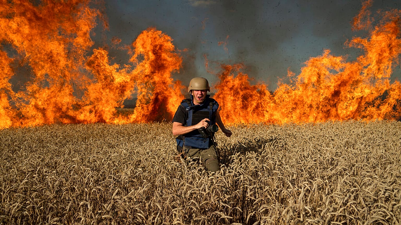 A journalist runs from a burning wheat field during his assignment after Russian shelling, a few kilometres from Ukrainian-Russian border in the Kharkiv region, July 29, 2022.