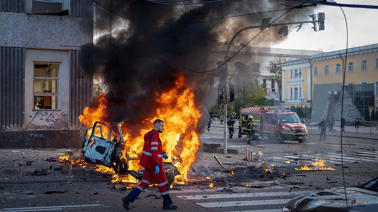 Un travailleur médical marche à côté d'une voiture qui brûle suite aux attaques à Kyiv, le 10 octobre 2022.