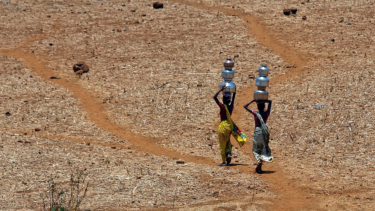 Deux Indiennes rentrent chez elles après avoir collecté de l'eau potable dans un puits à Mengal Pada, en Inde, en mai 2016. 