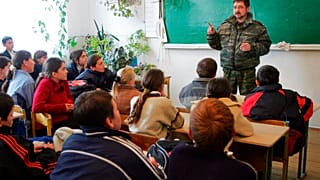 Orosz középiskolások hallgatják egy rendőrtiszt előadását