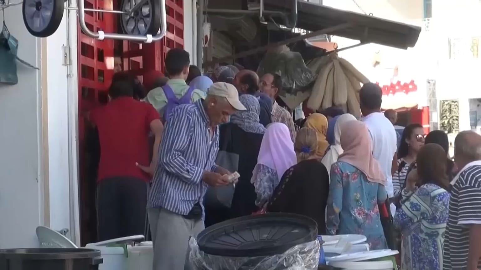 يتجمع الناس أمام محل تجاري لشراء المواد الغذائية 