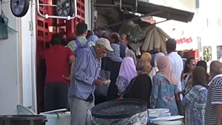 يتجمع الناس أمام محل تجاري لشراء المواد الغذائية 