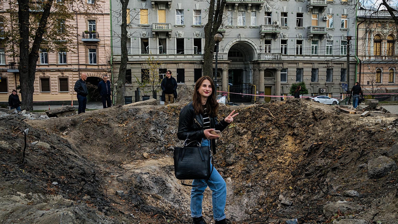 A woman poses for a photograph by a rocket crater in a park of central Kyiv.