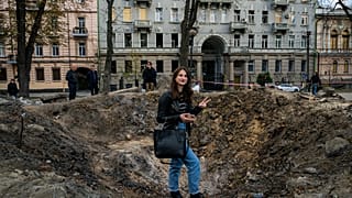 A woman poses for a photograph by a rocket crater in a park of central Kyiv.