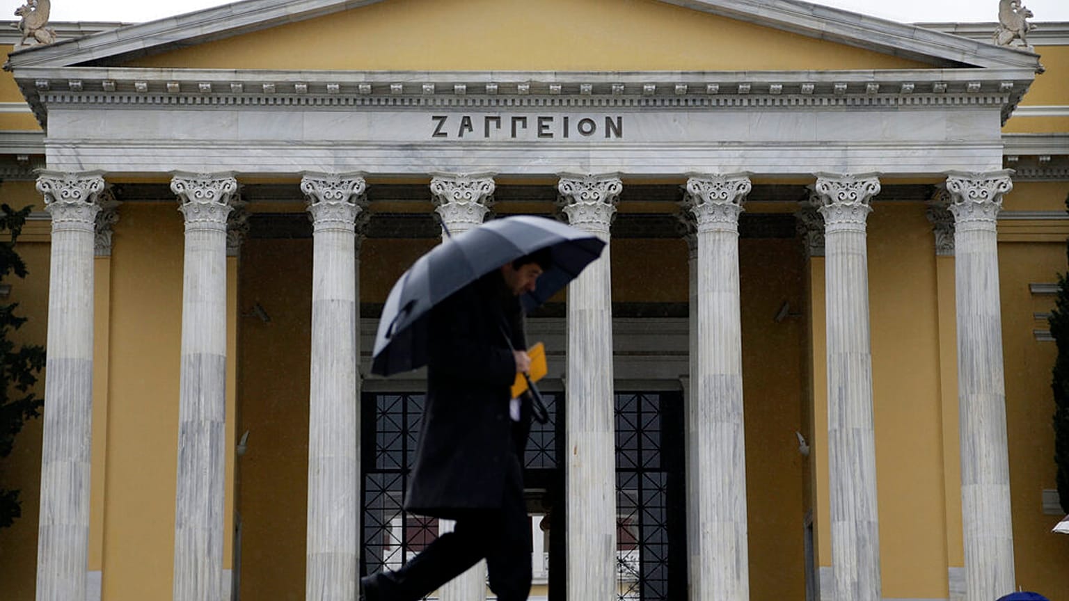 Πεζός με ομπρέλα για να προστατευθεί από την βροχή στο Ζάππειο Μέγαρο στην Αθήνα
