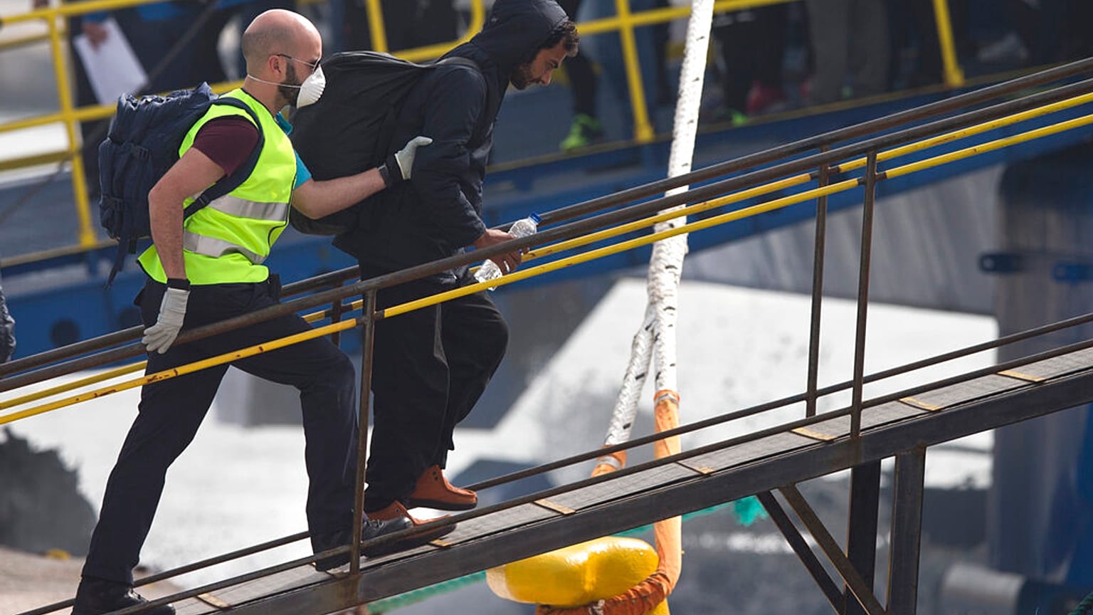 FILE - An officer from the European Union's border protection agency, Frontex, leads a migrant as they get in a ferry in the port of Mytilini, Lesbos island , Greece